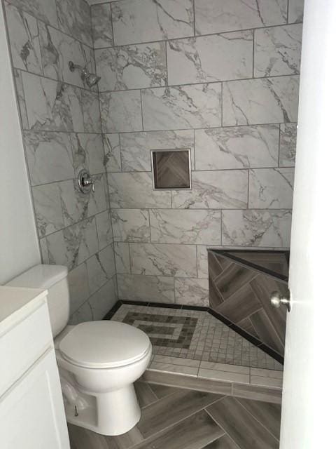 bathroom with a tile shower, vanity, toilet, and tile patterned floors