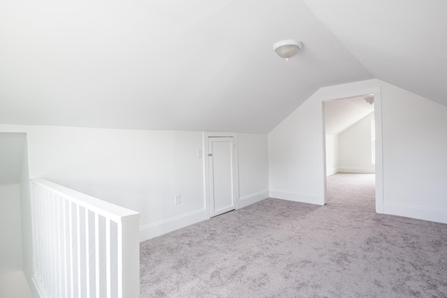 additional living space featuring light colored carpet and vaulted ceiling