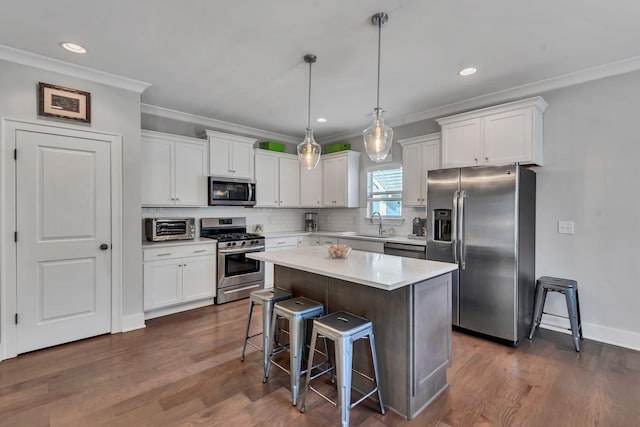 kitchen with a center island, decorative backsplash, appliances with stainless steel finishes, decorative light fixtures, and white cabinetry