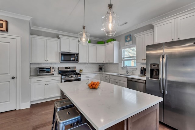 kitchen with sink, decorative light fixtures, a kitchen island, a kitchen bar, and stainless steel appliances