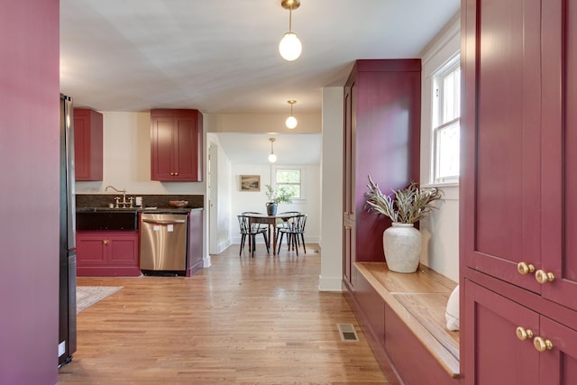 kitchen featuring pendant lighting, light wood-type flooring, sink, and appliances with stainless steel finishes