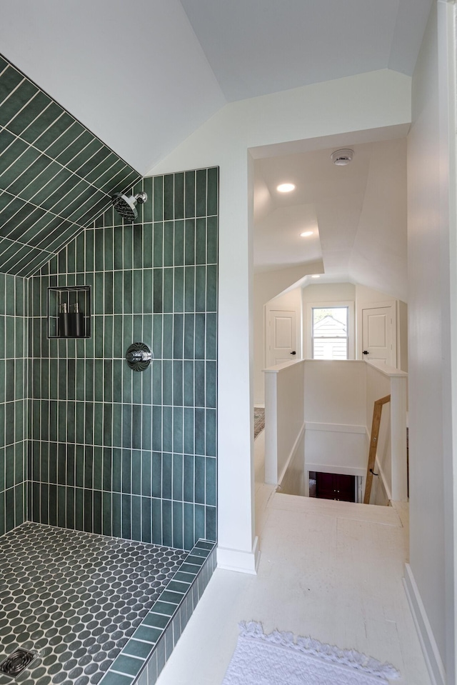 bathroom featuring lofted ceiling and tiled shower