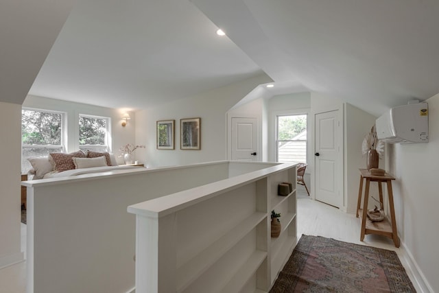 interior space with a wall mounted air conditioner, light hardwood / wood-style floors, and lofted ceiling