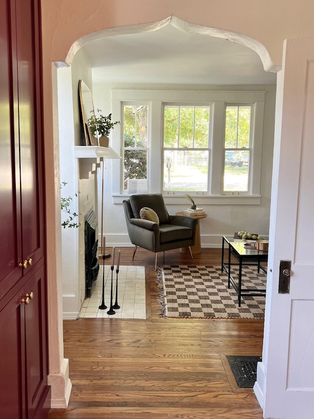 living area with a tiled fireplace, a wealth of natural light, and light hardwood / wood-style floors