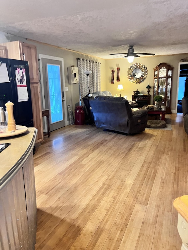 living room with light wood-type flooring, a textured ceiling, and ceiling fan