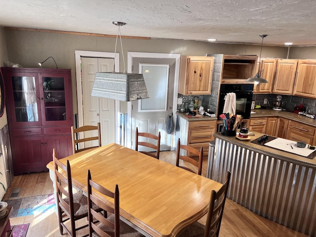 dining area with light hardwood / wood-style flooring and a textured ceiling