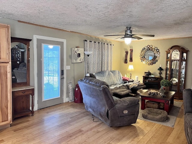 living room with a textured ceiling, light wood-type flooring, and ceiling fan