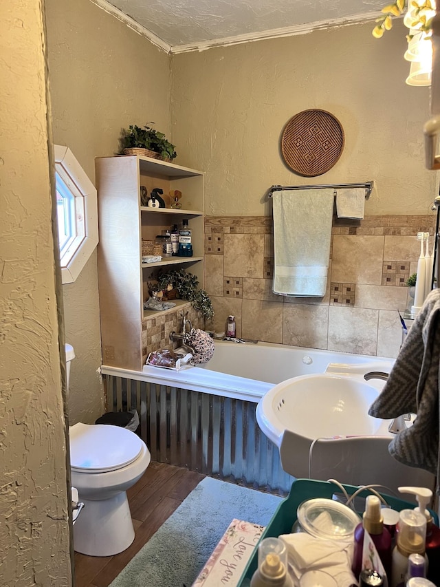 bathroom with crown molding, hardwood / wood-style floors, a textured ceiling, toilet, and tile walls