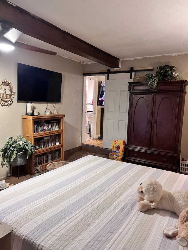 bedroom with beamed ceiling and a barn door