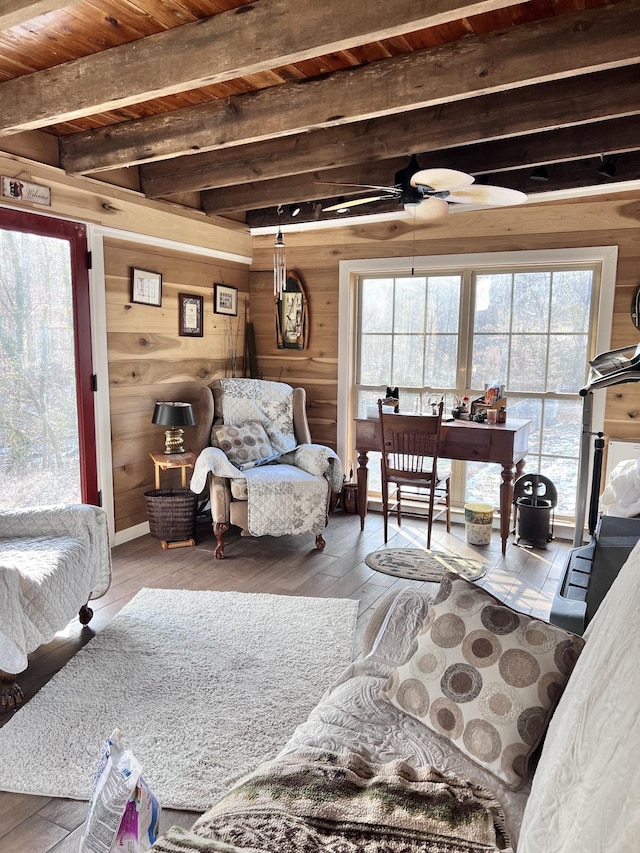 sitting room with beamed ceiling, plenty of natural light, wood walls, and wooden ceiling