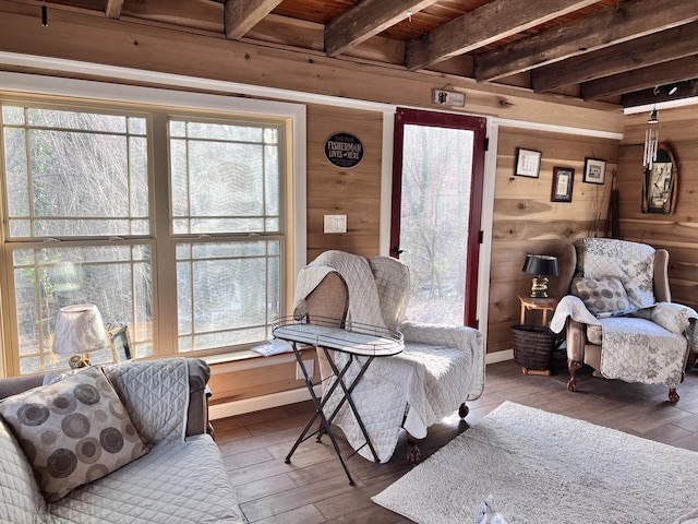 living area with hardwood / wood-style floors, wood ceiling, beamed ceiling, and wooden walls