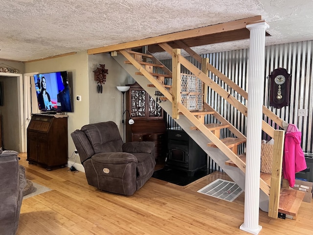 living room with wood-type flooring, a textured ceiling, and a wood stove