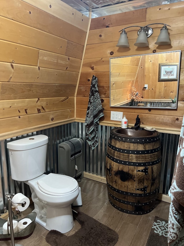 bathroom with hardwood / wood-style floors, toilet, and wood walls