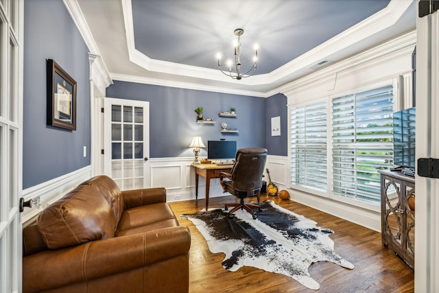 office space featuring ornamental molding, an inviting chandelier, a raised ceiling, and dark wood-type flooring