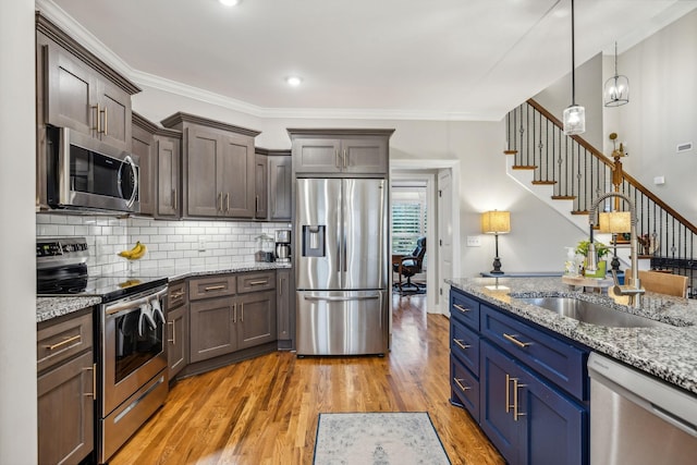 kitchen featuring sink, light stone counters, pendant lighting, appliances with stainless steel finishes, and ornamental molding