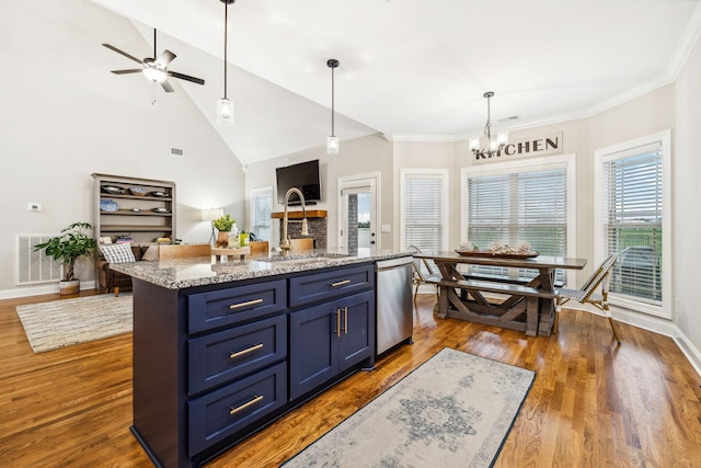 kitchen with sink, light stone counters, stainless steel dishwasher, blue cabinets, and a center island with sink