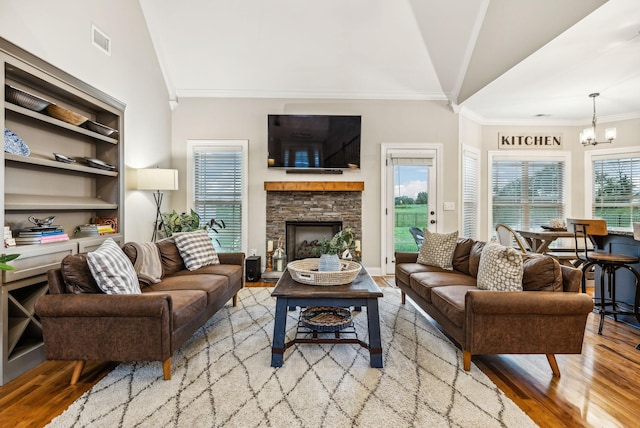 living room with lofted ceiling, crown molding, built in shelves, light wood-type flooring, and a chandelier