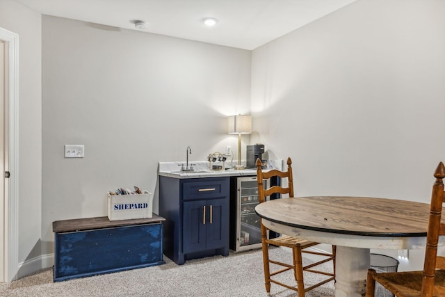 interior space with blue cabinetry, wine cooler, sink, and light colored carpet