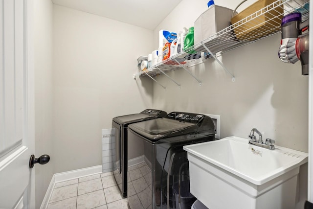 laundry area featuring washing machine and clothes dryer, sink, and light tile patterned flooring