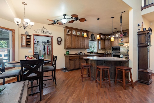 kitchen featuring a breakfast bar, appliances with stainless steel finishes, dark hardwood / wood-style flooring, and pendant lighting