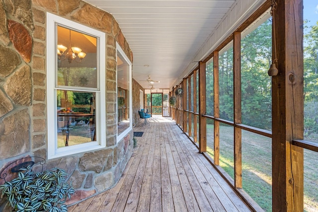 unfurnished sunroom with ceiling fan with notable chandelier