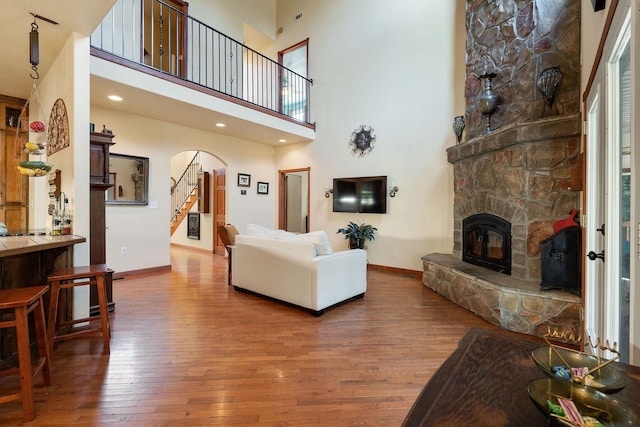 living room with hardwood / wood-style floors, a towering ceiling, and a fireplace