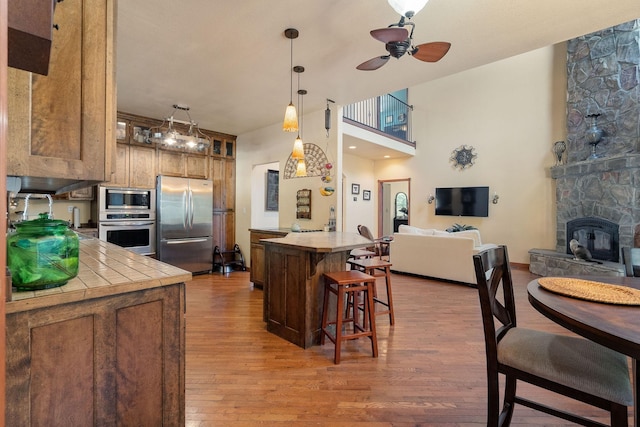 kitchen featuring a kitchen bar, appliances with stainless steel finishes, kitchen peninsula, ceiling fan, and hardwood / wood-style flooring