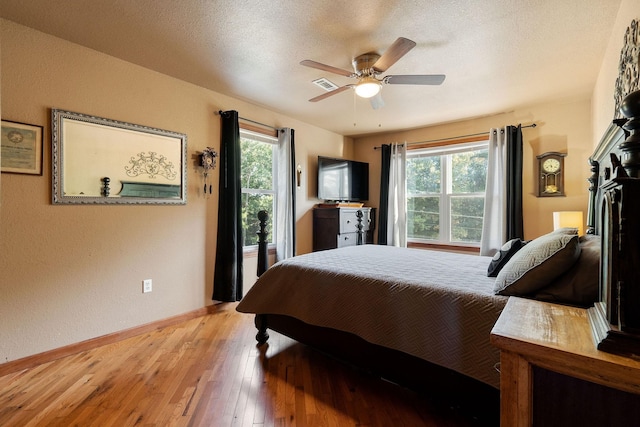 bedroom with ceiling fan, light hardwood / wood-style floors, and a textured ceiling