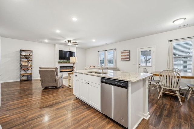 kitchen with light stone countertops, white cabinets, sink, a center island with sink, and dishwasher