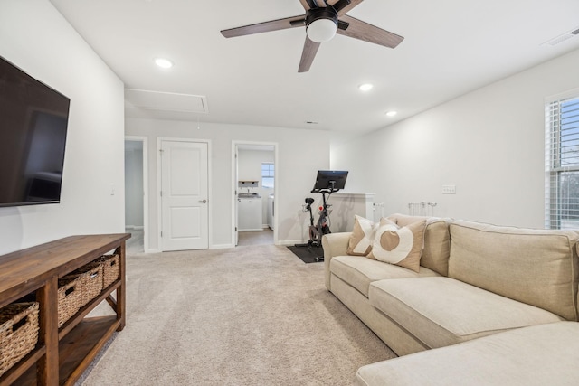 living room with washer / clothes dryer, light carpet, and ceiling fan