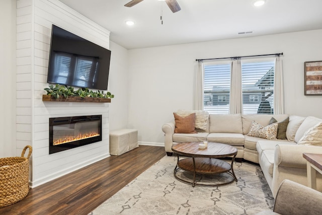 living room featuring a fireplace, ceiling fan, and dark hardwood / wood-style flooring