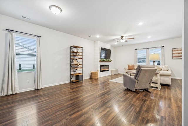 living room featuring ceiling fan, a fireplace, and dark hardwood / wood-style floors