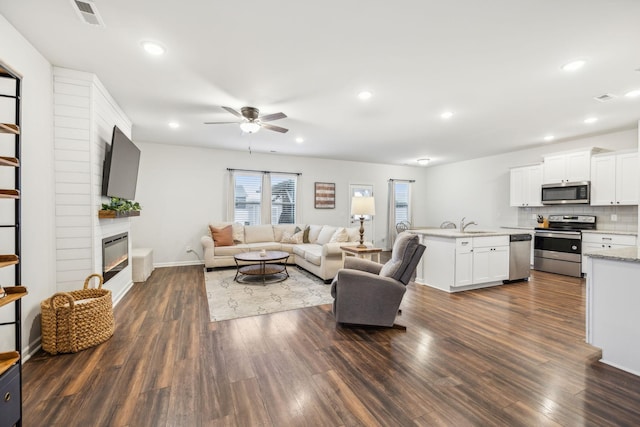 living room with ceiling fan, dark hardwood / wood-style floors, and a fireplace