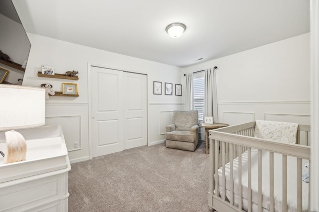 bedroom featuring a closet, light carpet, and a nursery area