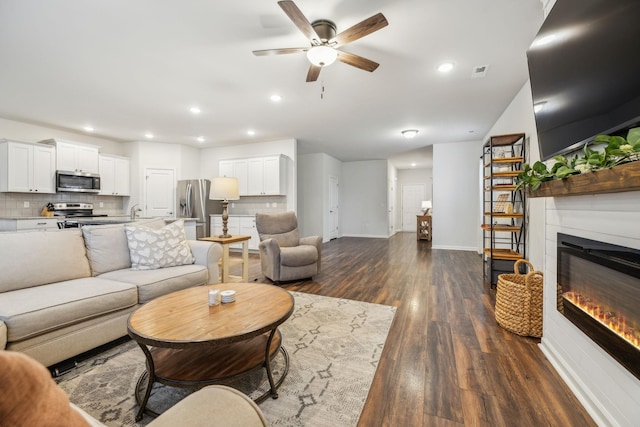 living room featuring ceiling fan and dark wood-type flooring