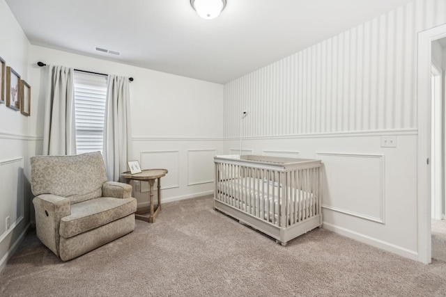 carpeted bedroom featuring a nursery area