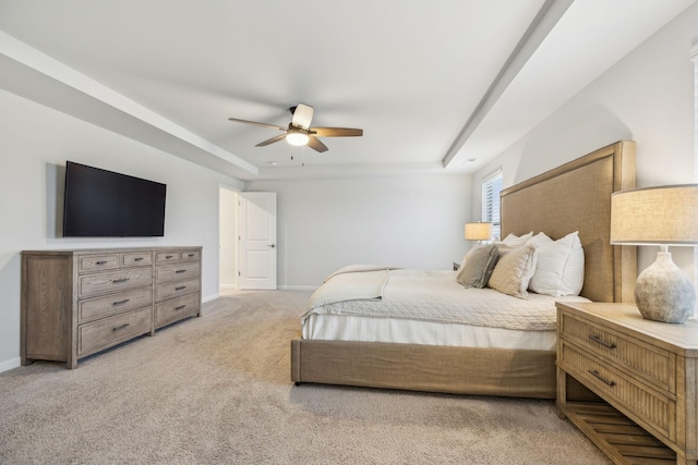 bedroom with light colored carpet, a raised ceiling, and ceiling fan