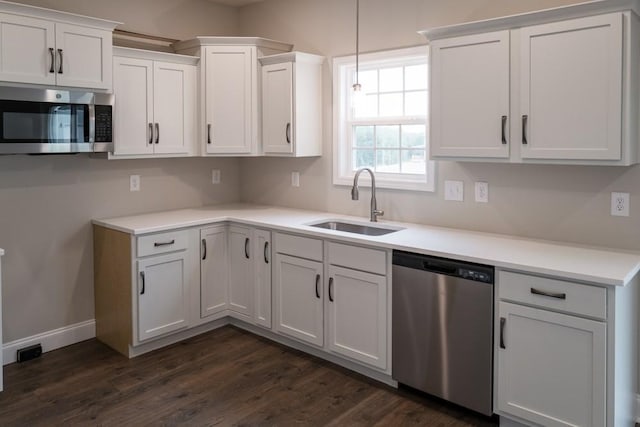 kitchen featuring white cabinetry, sink, hanging light fixtures, dark wood-type flooring, and appliances with stainless steel finishes