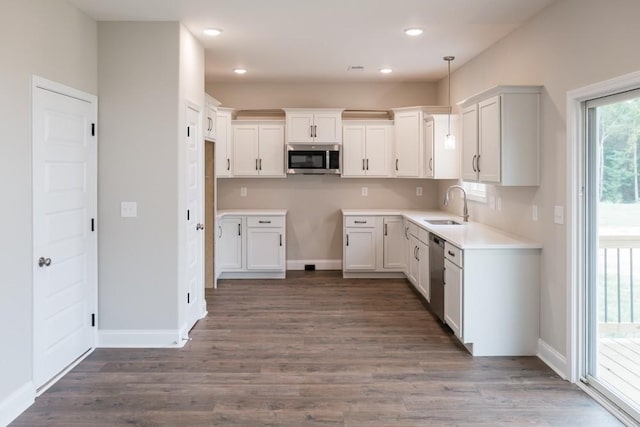 kitchen featuring sink, white cabinets, stainless steel appliances, and decorative light fixtures