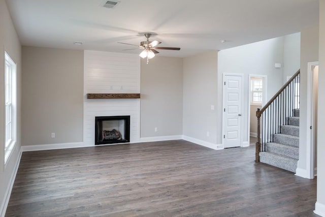 unfurnished living room with ceiling fan, a large fireplace, and dark hardwood / wood-style floors