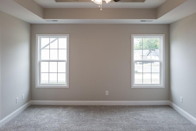 carpeted spare room featuring a tray ceiling and ceiling fan