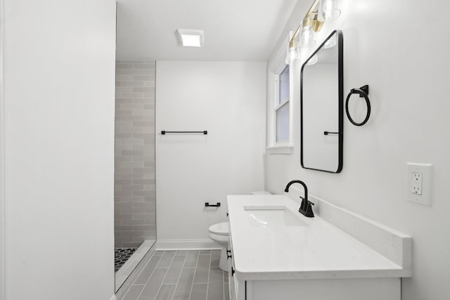 bathroom with vanity, toilet, and a tile shower