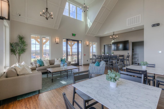 dining area with french doors, a towering ceiling, and wood-type flooring