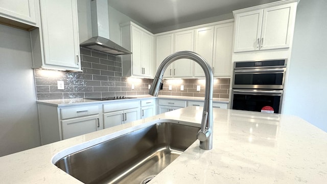 kitchen with white cabinetry, light stone counters, and wall chimney range hood