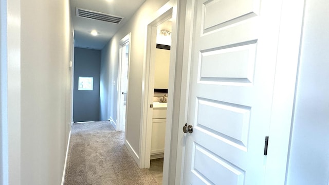 hallway featuring light colored carpet and sink