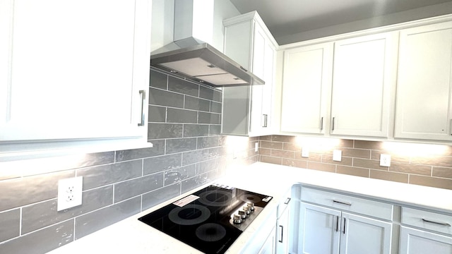 kitchen with tasteful backsplash, white cabinets, black electric stovetop, and wall chimney exhaust hood