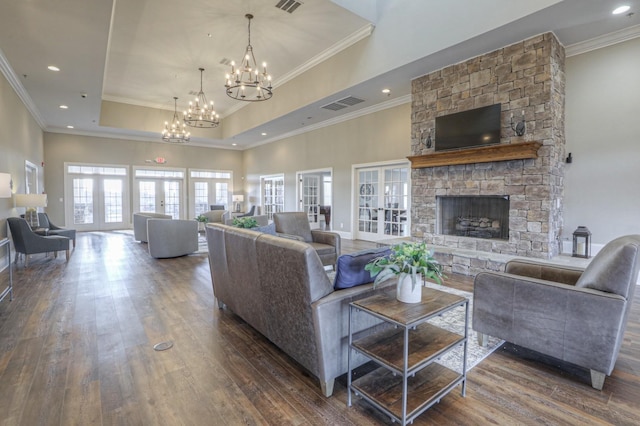 living room with french doors, dark hardwood / wood-style flooring, a tray ceiling, an inviting chandelier, and a fireplace