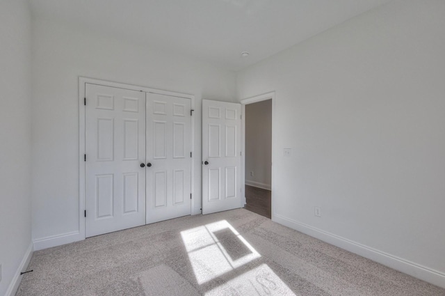 unfurnished bedroom featuring light colored carpet and a closet