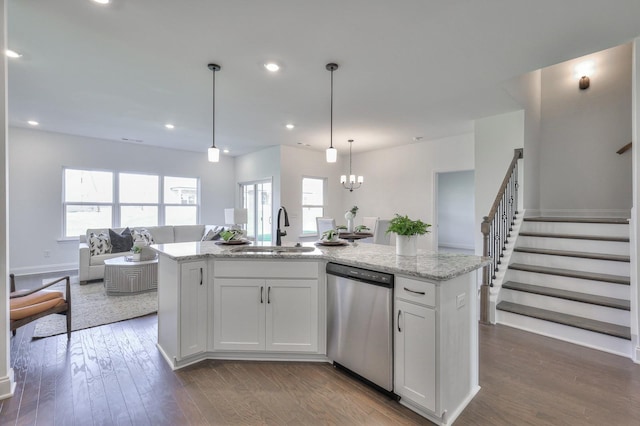 kitchen featuring dishwasher, a kitchen island with sink, sink, light stone countertops, and white cabinetry