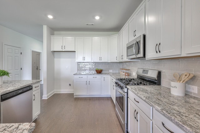 kitchen with white cabinets, appliances with stainless steel finishes, and light stone countertops